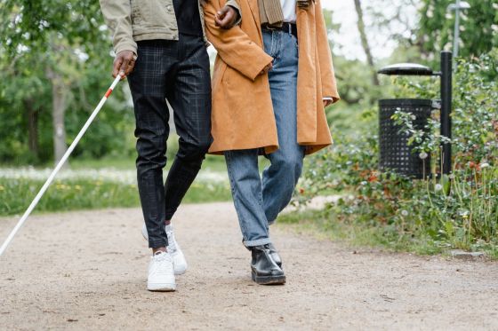 blind man walking with signed woman